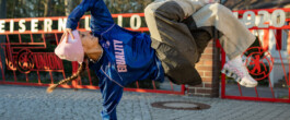 Jilou Rasul in the blue Fan for Female jersey, mid-movement in front of a stadium gate 