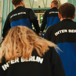 Group in Inter Berlin tracksuit jackets with INTER BERLIN lettering on the back, climbing stairs