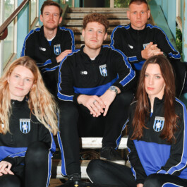 Five people in Inter Berlin tracksuit jackets sitting together on a staircase